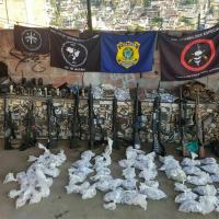 Armas e drogas apreendidas nas operações da Vila Cruzeiro. Ao fundo as organizações militares que participaram da operação. 